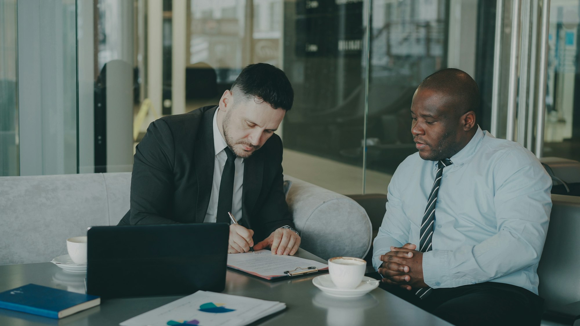 Two people reviewing and signing documents together at a desk